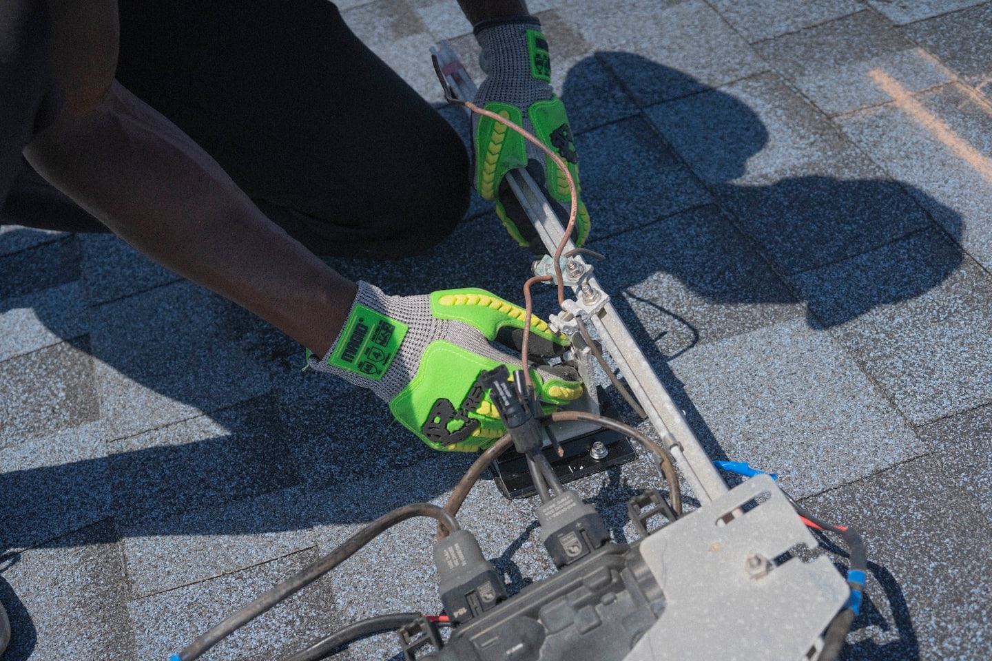 Mains gantées installant des panneaux solaires sur un toit.